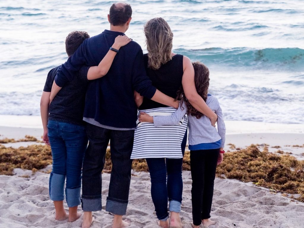 Family of four on the beach, looking out to sea