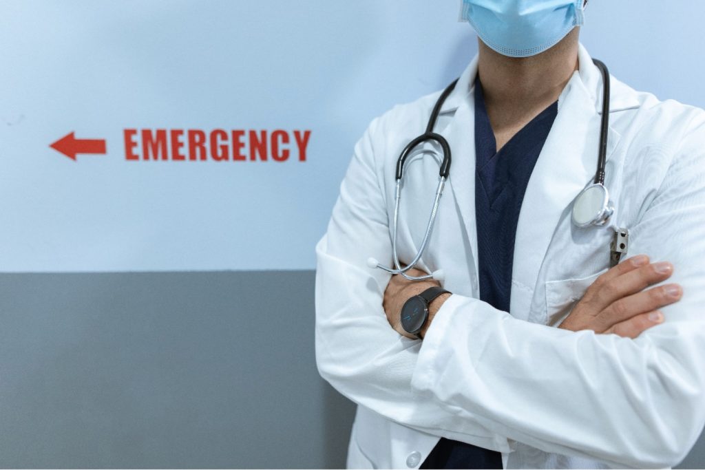 Hospital doctor standing next to an emergency department sign