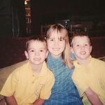 Three children seated on a lounge, looking to camera and smiling