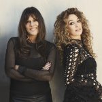 Two women dressed in black and looking to camera