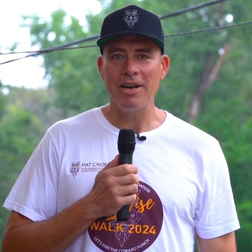 Man holding a microphone, looking at the camera